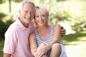 happy senior couple relaxing in park with healthy smiles