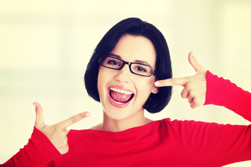 Smiling woman pointing at her straight teeth excitedly