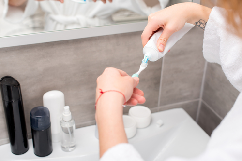 woman squeezing toothpaste onto the toothbrush