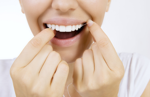 young woman close up flossing her teeth