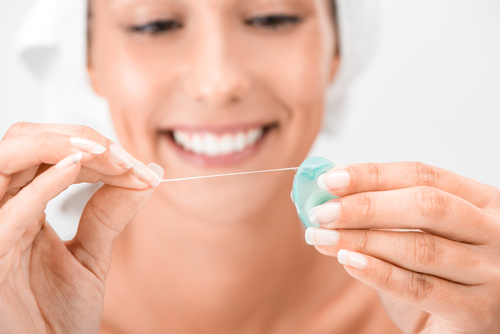 woman smiling and holding dental floss container