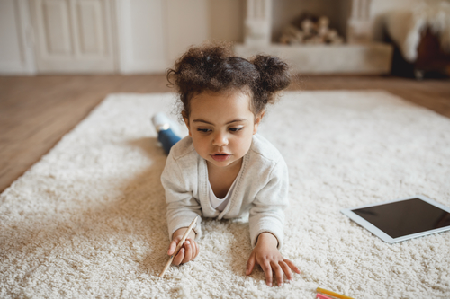 little girl laying on the rug with pencil in hand