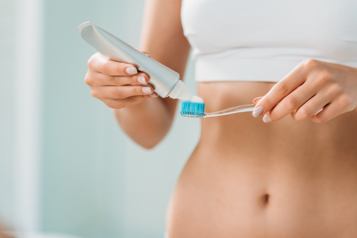 woman putting toothpaste on a toothbrush