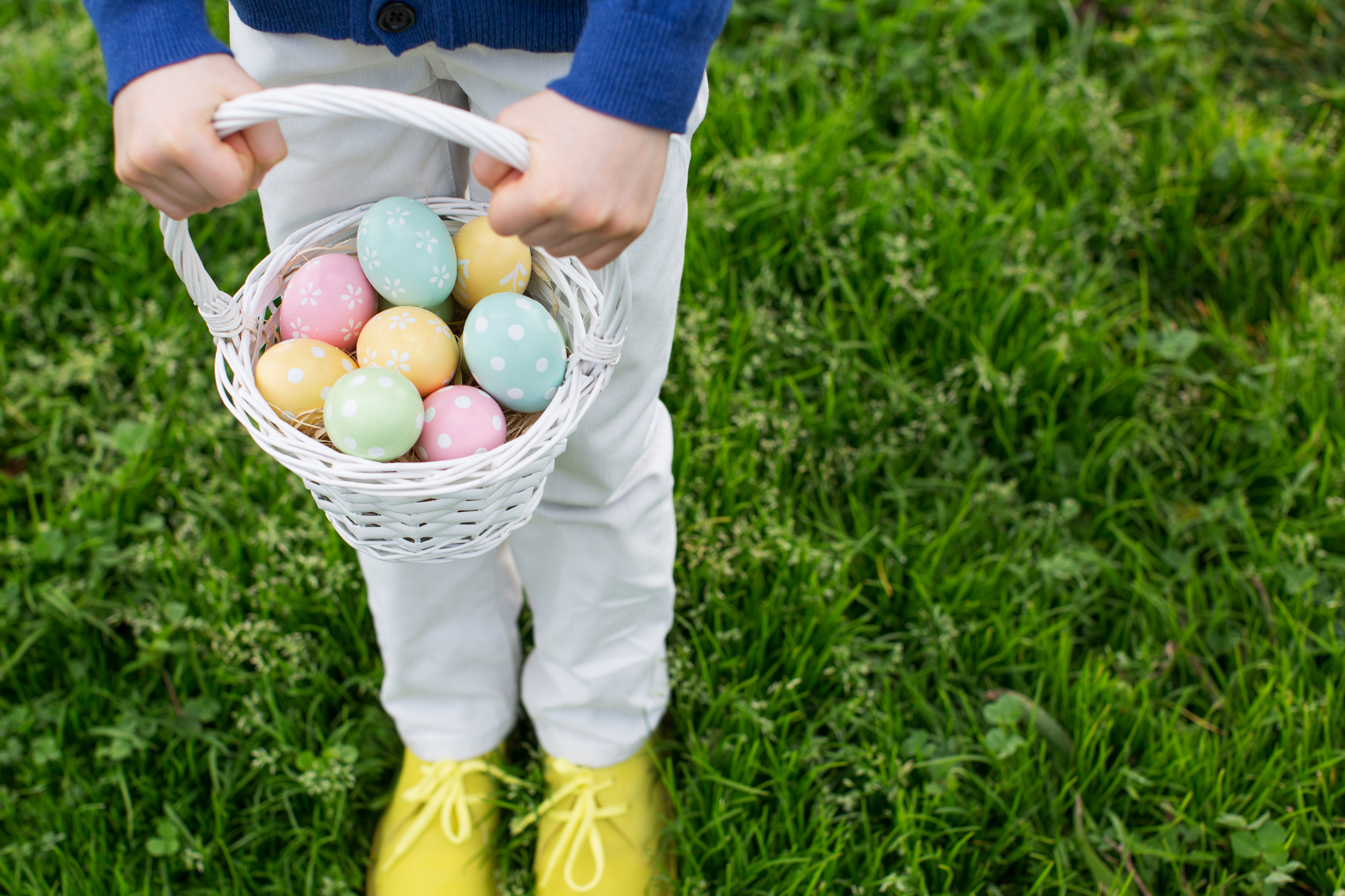 ggs in easter basket being held by little boy after easter egg hunt