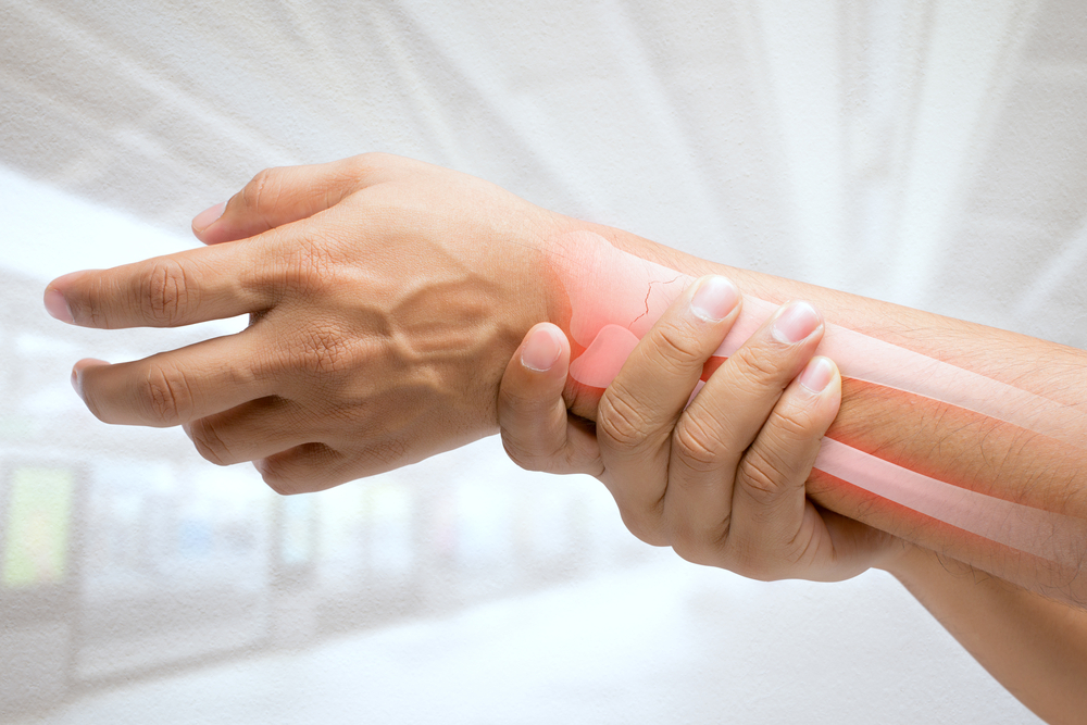 man holding painful wrist due to osteoporosis