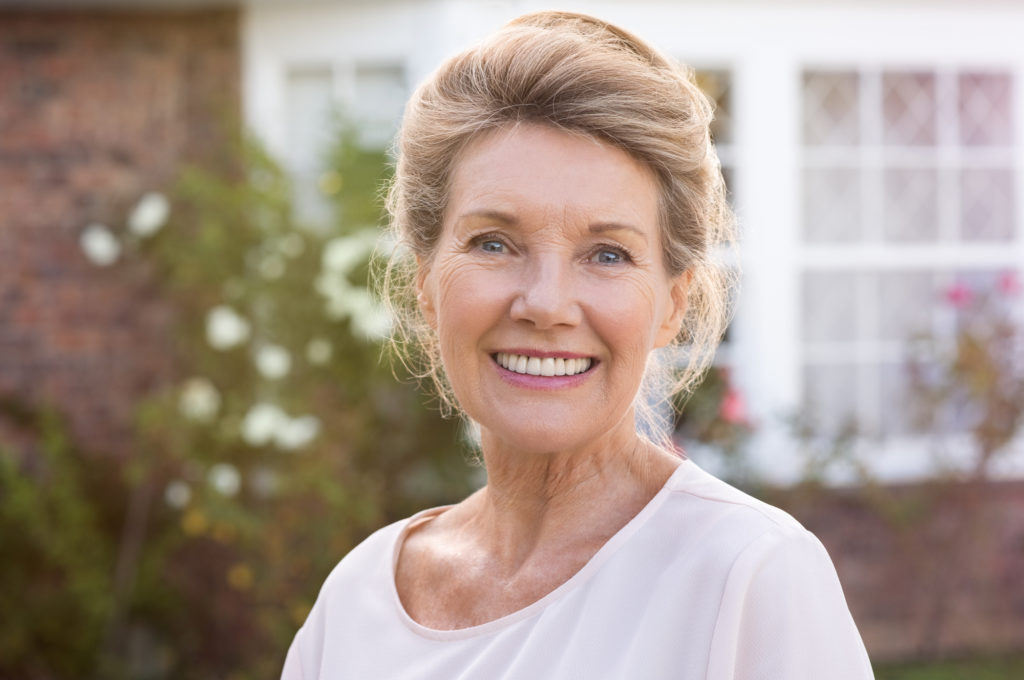 senior woman smiling outside her house