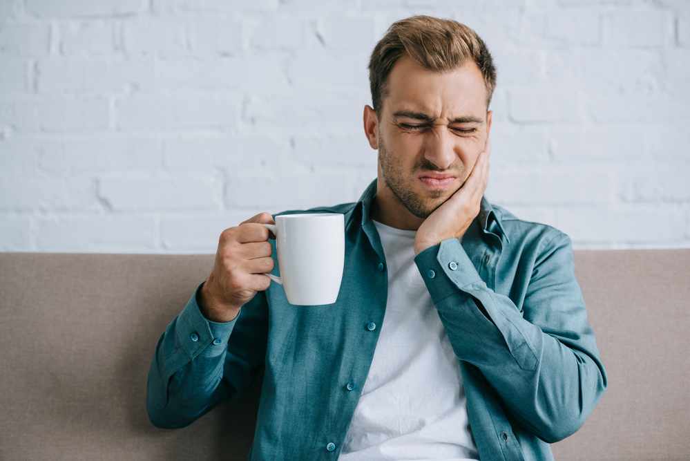 man touching sore jaw and wincing