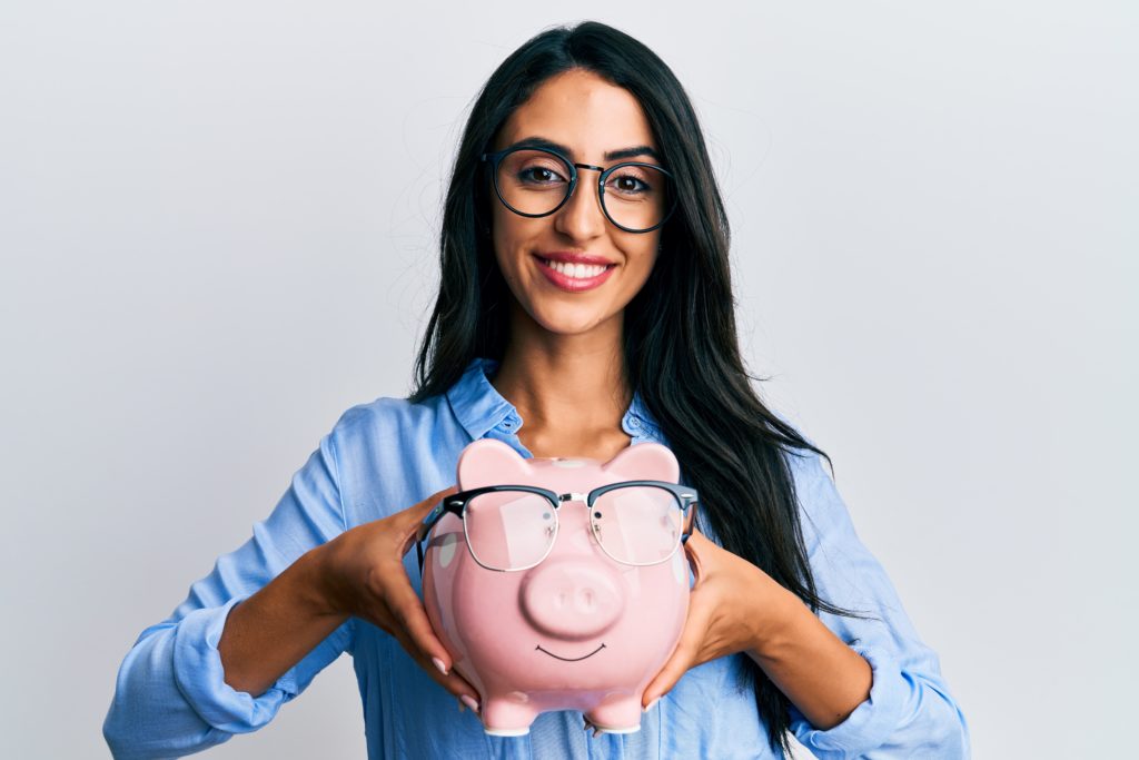 Young woman smiling with straight white smile and piggy bank