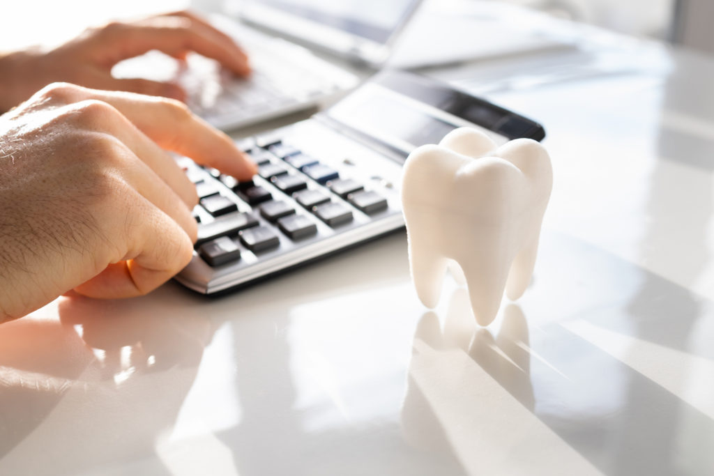 Patient calculating the cost of dental implants on a calculator.