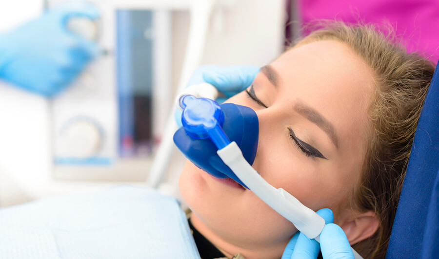 woman breathing in nitrous oxide in the dental chair through a nose mask