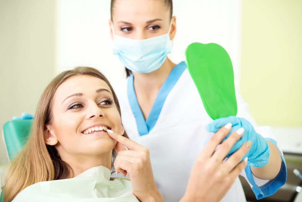 Dentist and patient looking at temporary crown. 