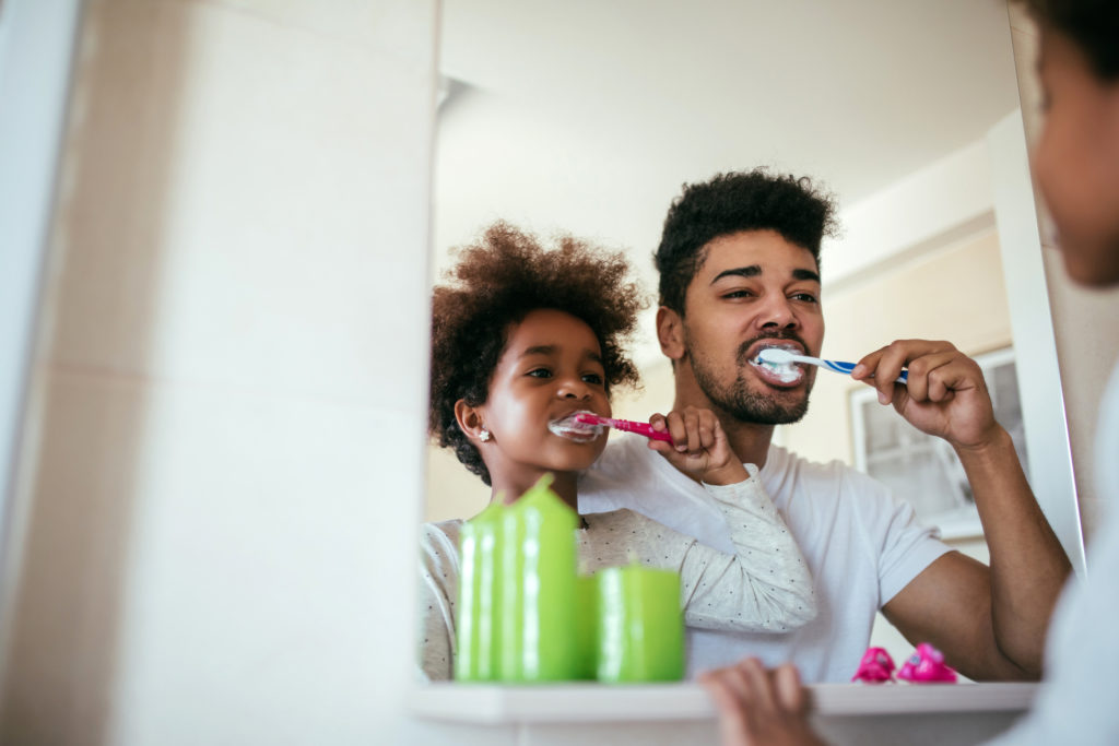 Family brushing teeth with fluoride toothpaste.