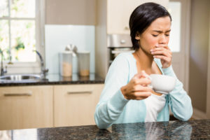 Woman with sensitive teeth reacting to hot coffee. 
