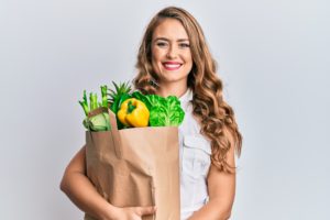 Young woman with healthy groceries with a confident smile and healthy teeth