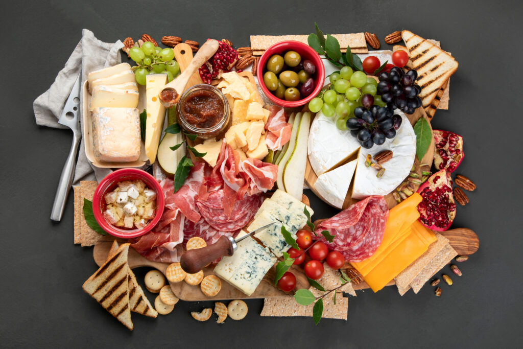 Healthy charcuterie board with meats, cheeses, fruits, and veggies.
