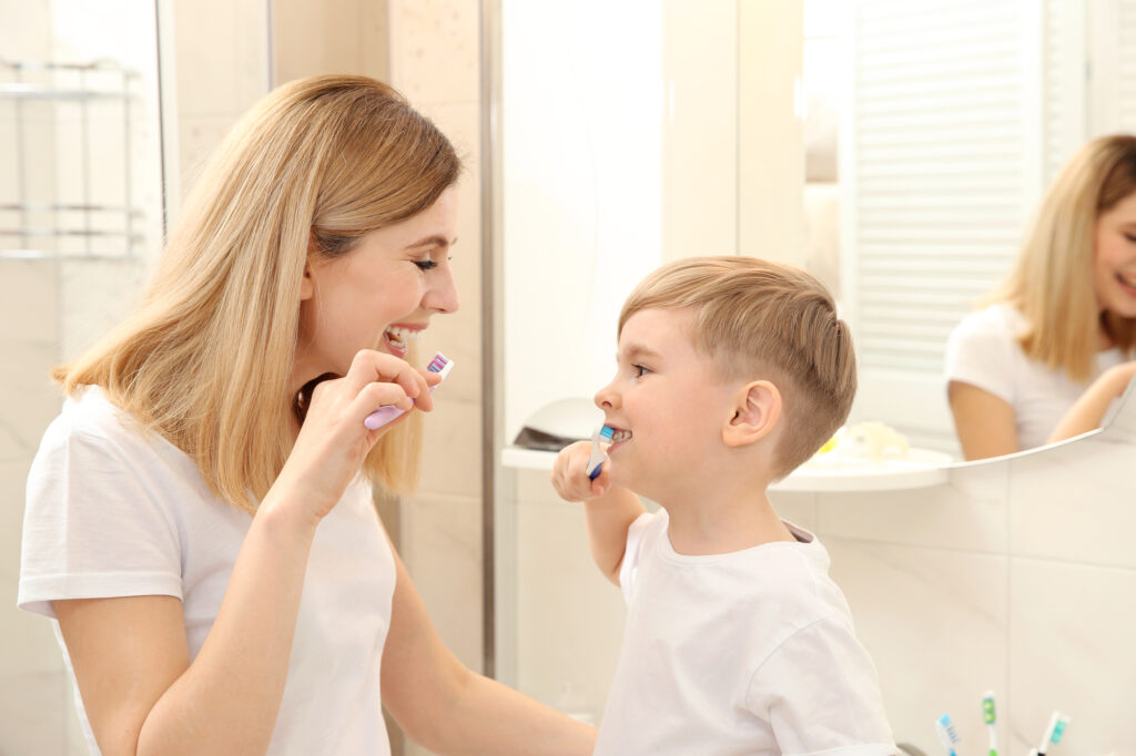 Mother helping son with sensory issues brush teeth. 