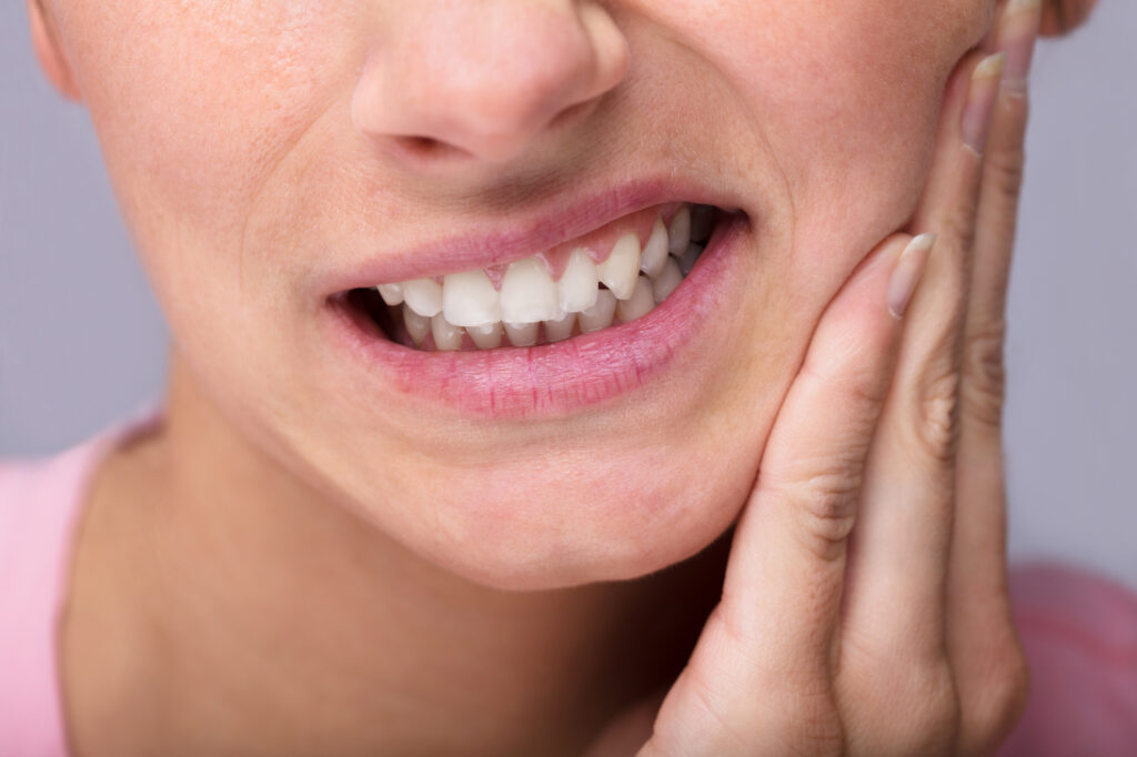 Young woman holding cheek from sensitive teeth 