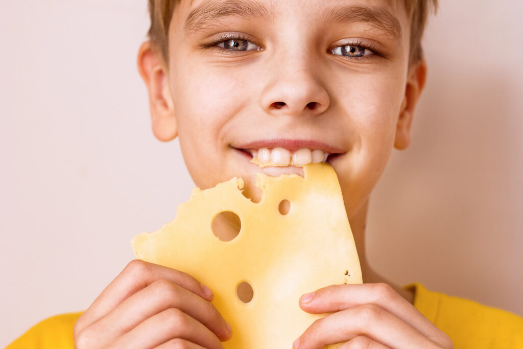 Young boy with healthy teeth eating cheese.