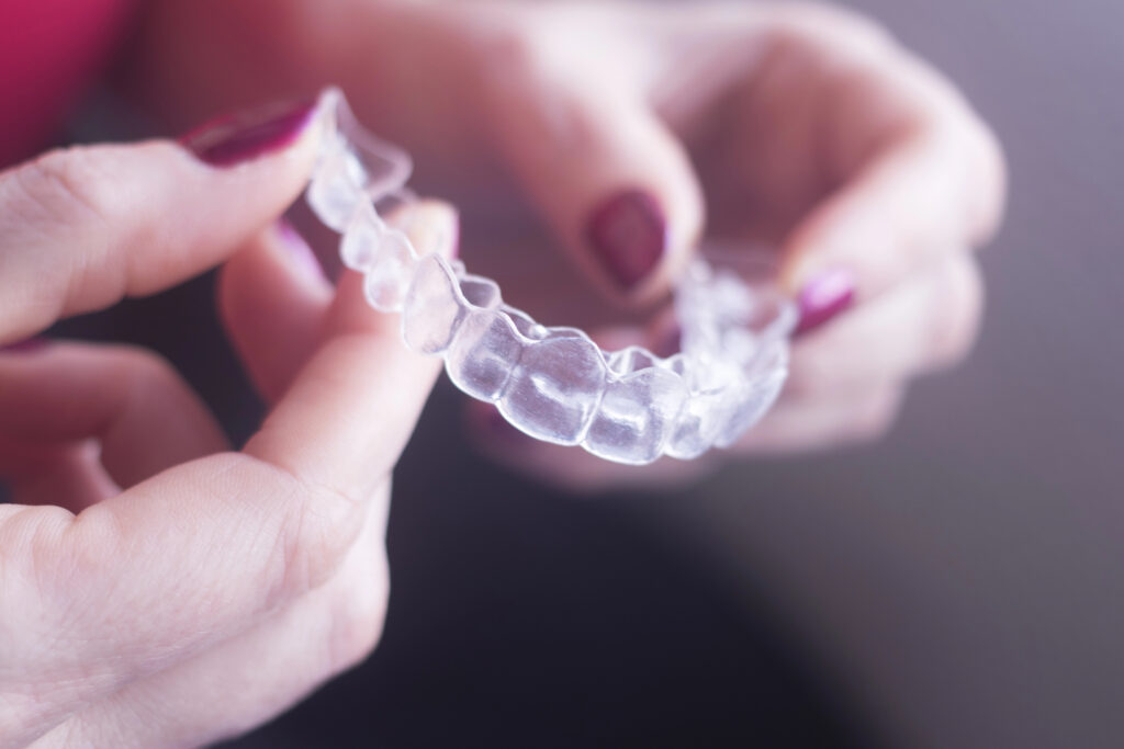 Close up of woman's hands holding Invisalign aligners. 