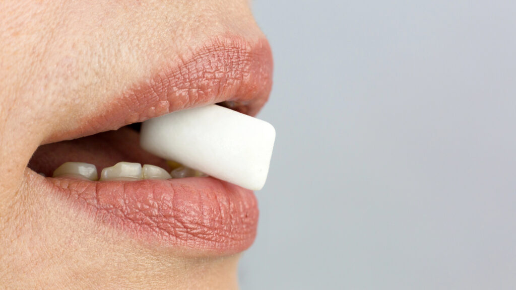 Close up of person's mouth with breath mint. 