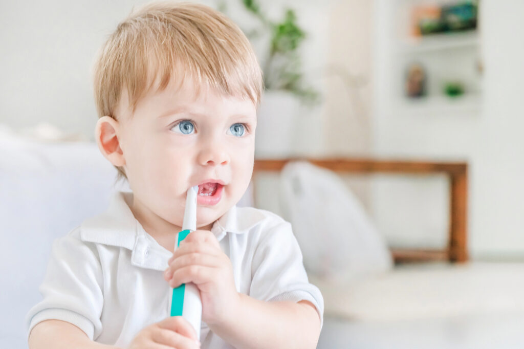 Toddler brushing teeth and eating toothpaste.