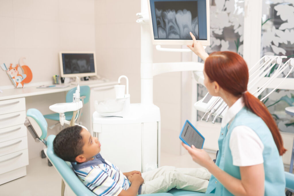 Pediatric dentist showing child their dental x-rays. 